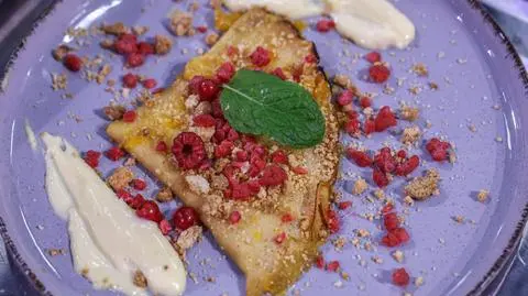 Crêpes Suzette z kruszonką z kremem z białej czekolady i mango, posypane malinami i czerwoną porzeczką w azocie