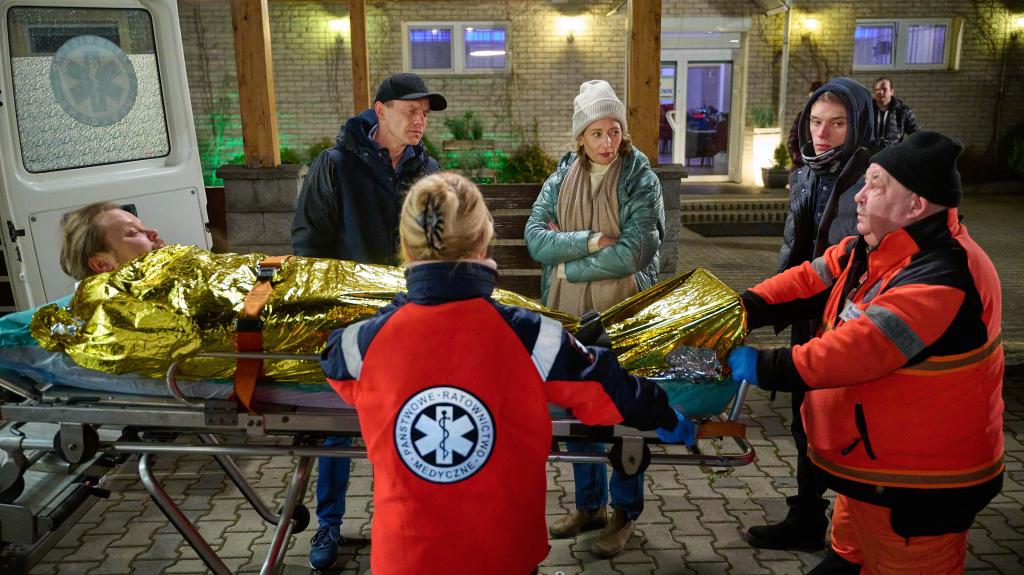 Kadr z serialu TVN Na Wspólnej. Odcinek 3595, Kamil Hoffer (Kazimierz Mazur) i terapeutka (Magdalena Popławska) stoją przy karetce pogotowia.
