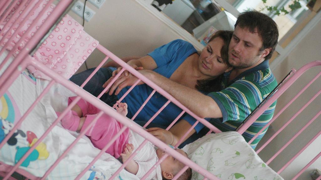 Zmartwieni rodzice czuwają przy łóżku swojej małej córeczki.